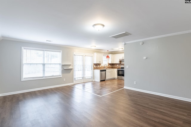 unfurnished living room with baseboards, dark wood-style flooring, visible vents, and crown molding