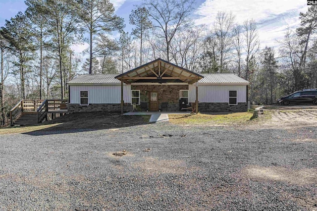 view of front of home with metal roof, stone siding, and a wooden deck