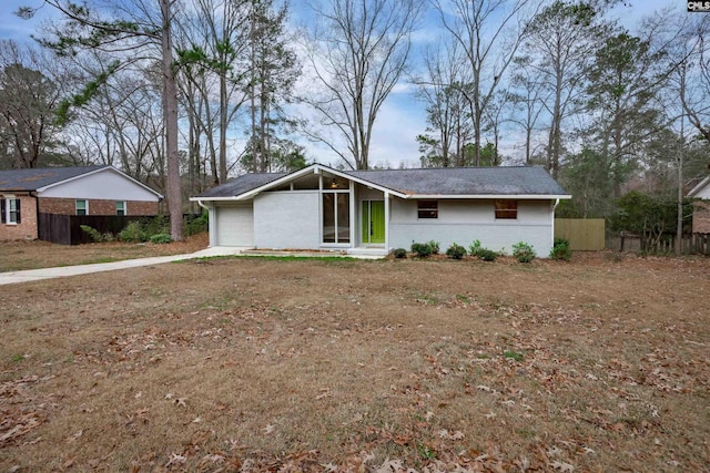 view of front of property featuring a garage, brick siding, driveway, and fence