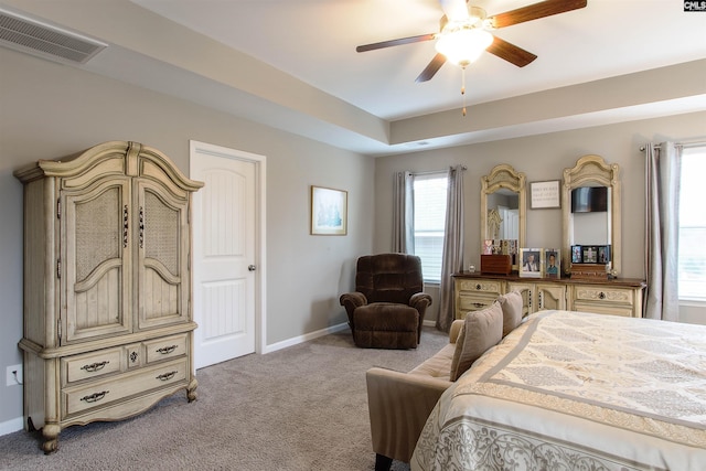 bedroom featuring baseboards, visible vents, a raised ceiling, a ceiling fan, and light colored carpet