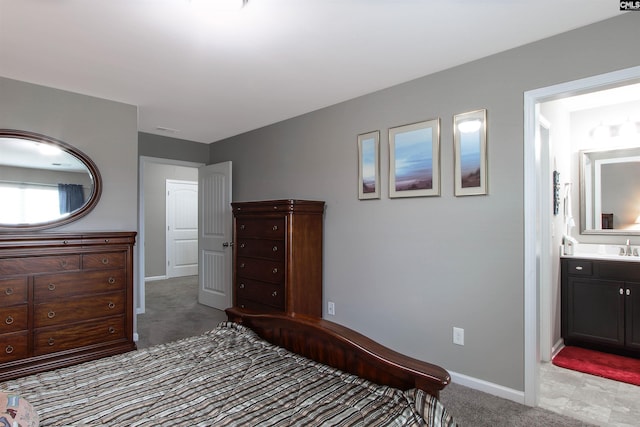 bedroom featuring light colored carpet, a sink, ensuite bath, and baseboards