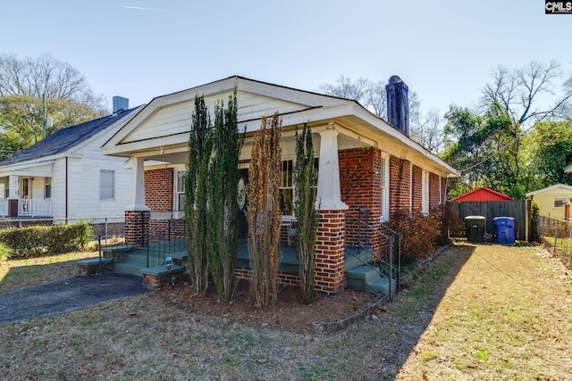 view of side of home with brick siding, a chimney, and fence