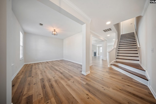 interior space featuring light wood-type flooring, visible vents, stairway, and baseboards