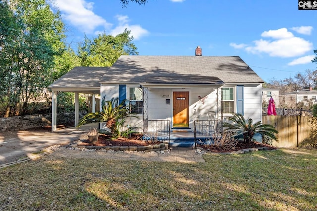 view of front of house featuring fence, concrete driveway, a carport, a front lawn, and a chimney