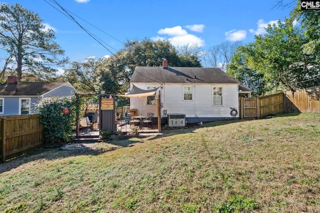 back of house with a yard, a chimney, and a fenced backyard