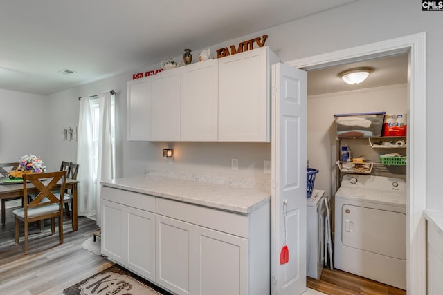 kitchen featuring light wood-style flooring, visible vents, white cabinetry, washer and dryer, and light countertops