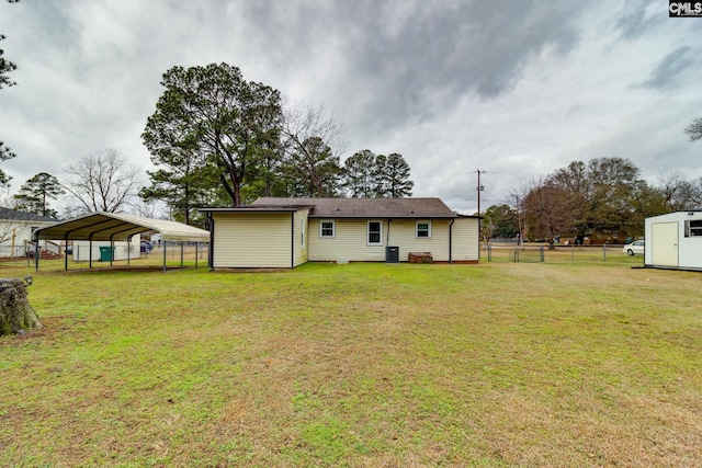 back of property featuring fence, an outbuilding, a carport, and a yard