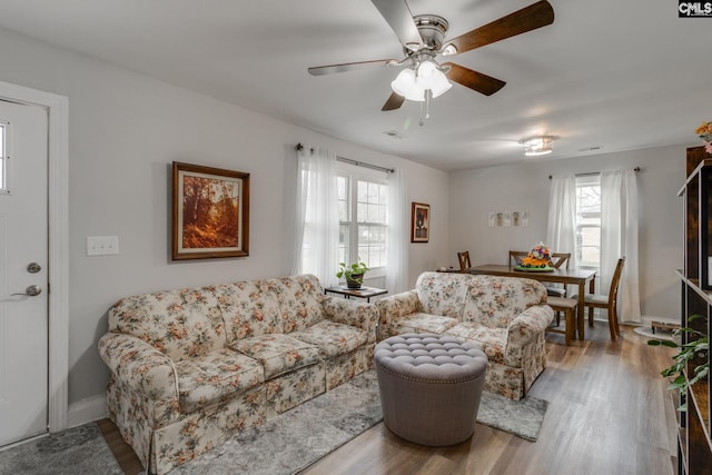 living area with ceiling fan, baseboards, and wood finished floors