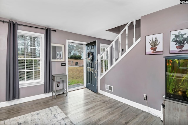 foyer with visible vents, stairway, baseboards, and wood finished floors