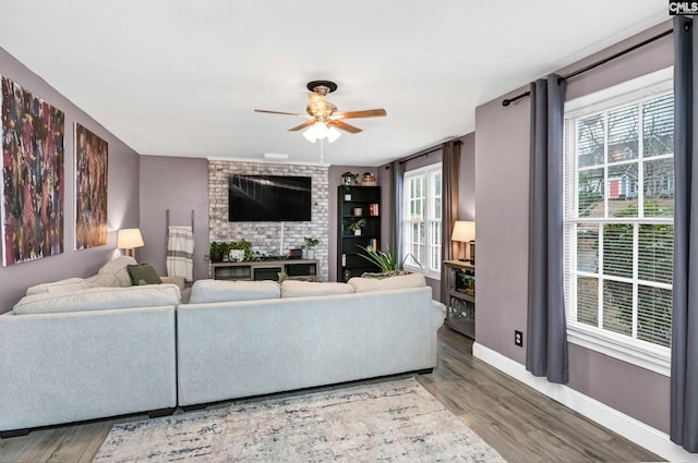 living room with wood finished floors, a ceiling fan, and baseboards