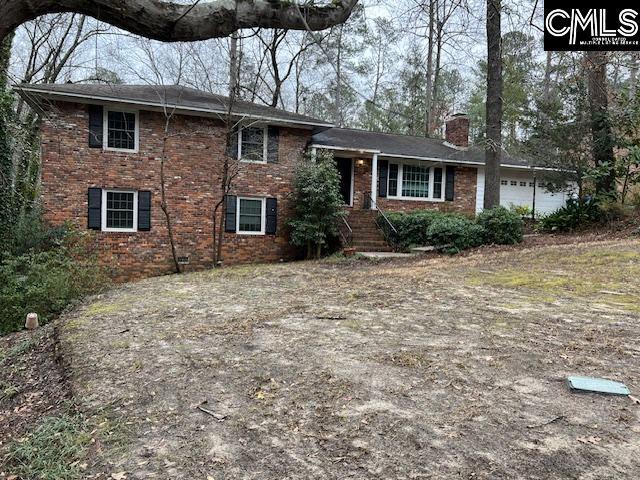 view of front of home with brick siding, a chimney, and an attached garage