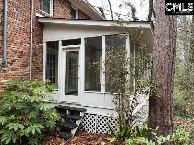 view of home's exterior featuring entry steps, a sunroom, and brick siding