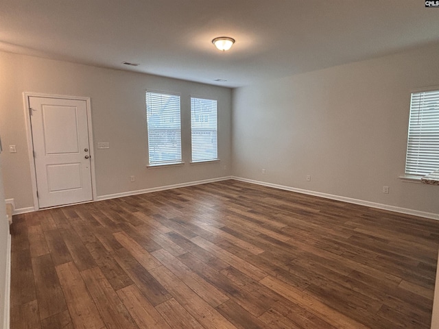 empty room featuring baseboards, visible vents, and dark wood-type flooring