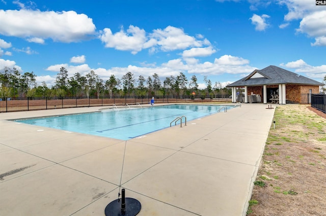 community pool with an outbuilding, a patio area, and fence