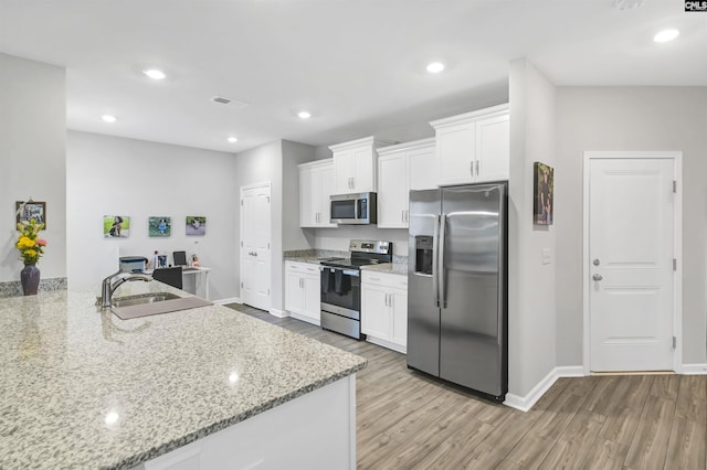 kitchen featuring visible vents, white cabinets, light wood-style flooring, appliances with stainless steel finishes, and light stone countertops