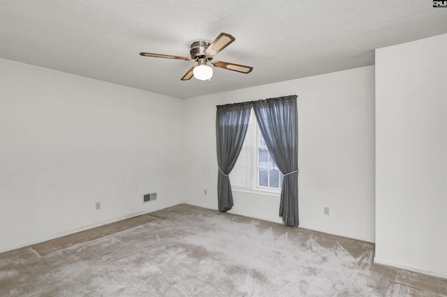 unfurnished room with light colored carpet, visible vents, ceiling fan, and a textured ceiling