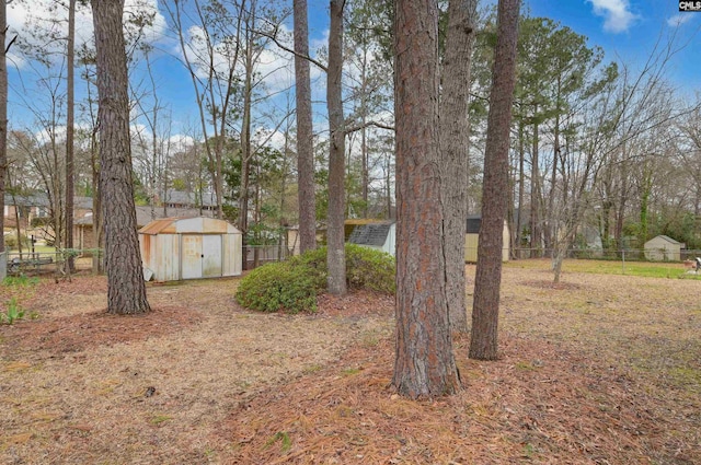 view of yard featuring an outdoor structure, fence, and a shed