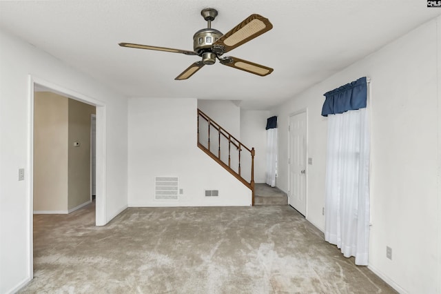 unfurnished room with light colored carpet, visible vents, ceiling fan, and stairway