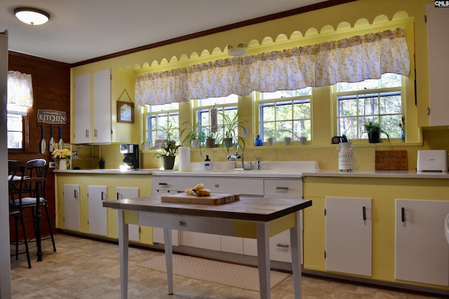 kitchen with crown molding, white cabinets, light countertops, and plenty of natural light