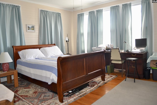 bedroom featuring ornamental molding, multiple windows, and wood finished floors