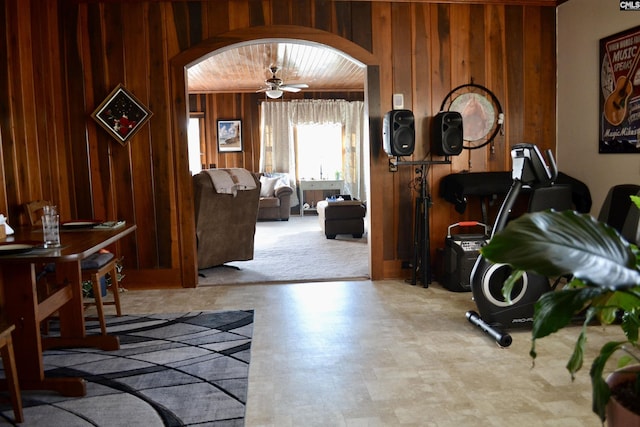 interior space featuring wood walls, arched walkways, and a ceiling fan