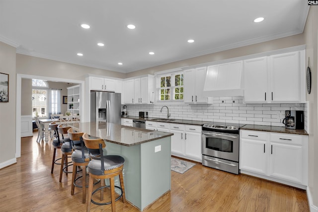 kitchen with stainless steel appliances, a sink, a center island, and white cabinets