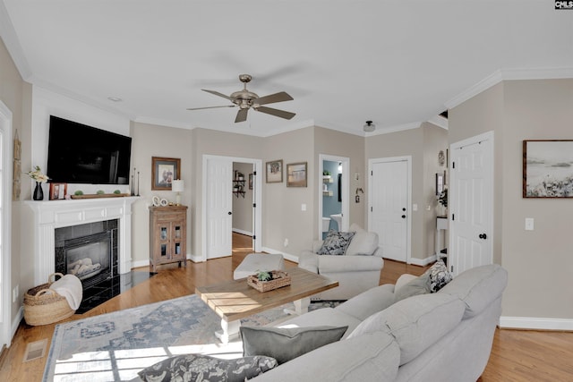 living room featuring baseboards, visible vents, ornamental molding, light wood-type flooring, and a fireplace