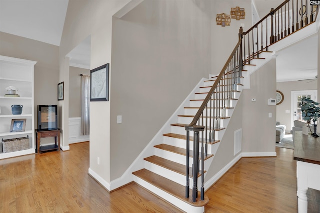 stairway featuring visible vents, a towering ceiling, and wood finished floors