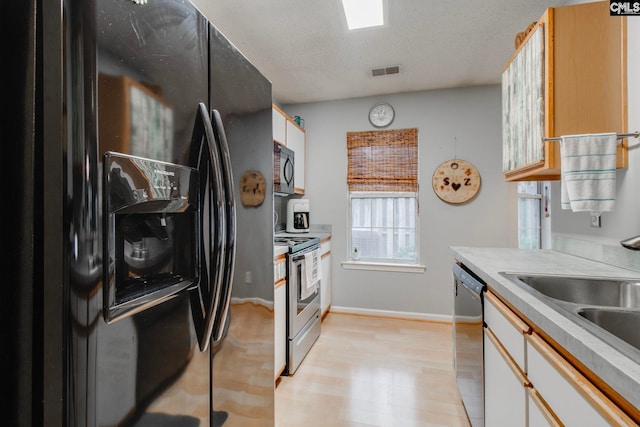 kitchen with black appliances, white cabinets, and light countertops