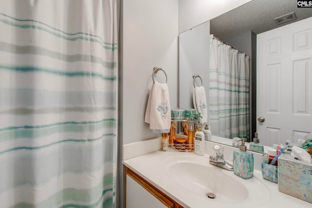 full bath with visible vents, a textured ceiling, and vanity