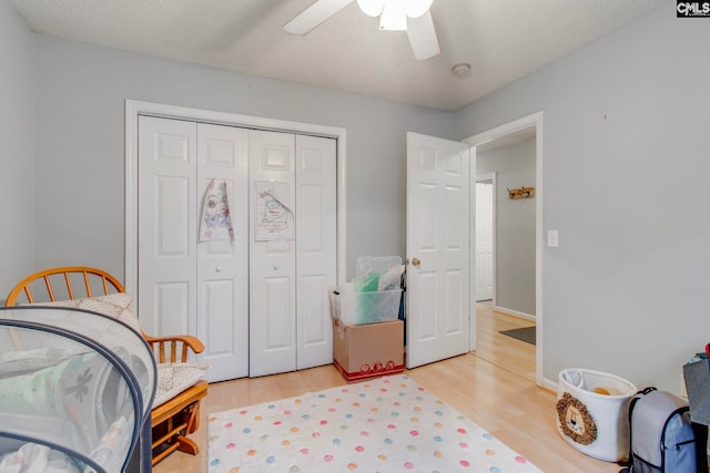 bedroom with a textured ceiling, light wood finished floors, a closet, and a ceiling fan