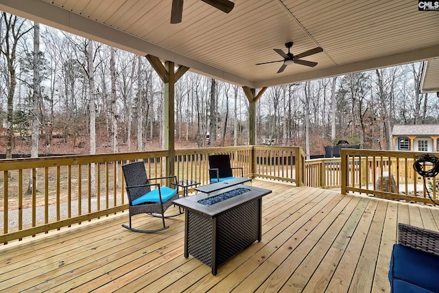 wooden terrace with a ceiling fan and a fire pit