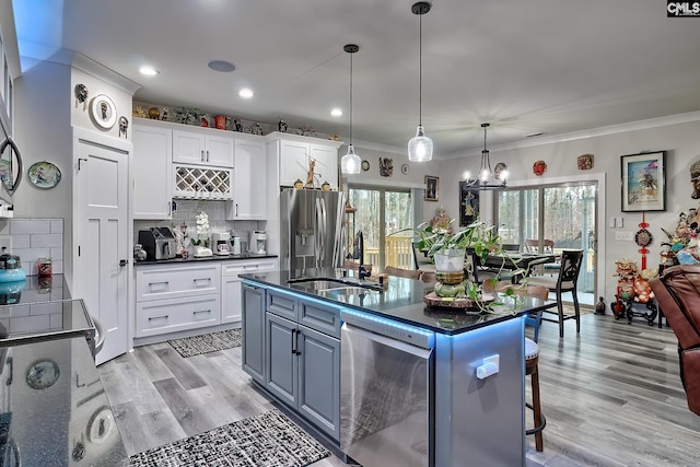 kitchen with stainless steel appliances, pendant lighting, white cabinetry, and a sink