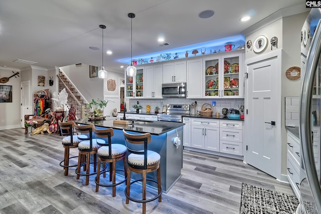 kitchen featuring dark countertops, appliances with stainless steel finishes, glass insert cabinets, decorative light fixtures, and white cabinetry