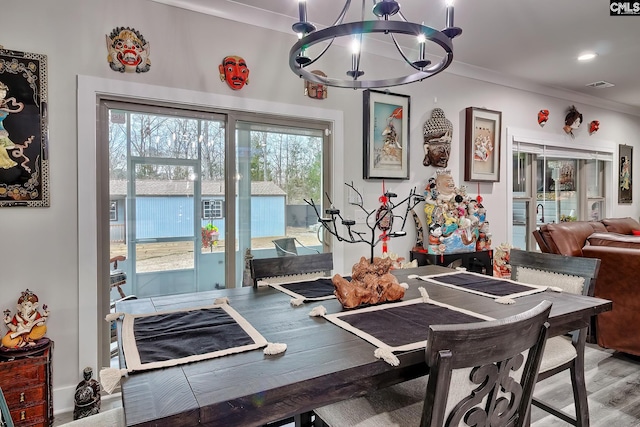 dining space with light wood finished floors, visible vents, crown molding, a notable chandelier, and recessed lighting