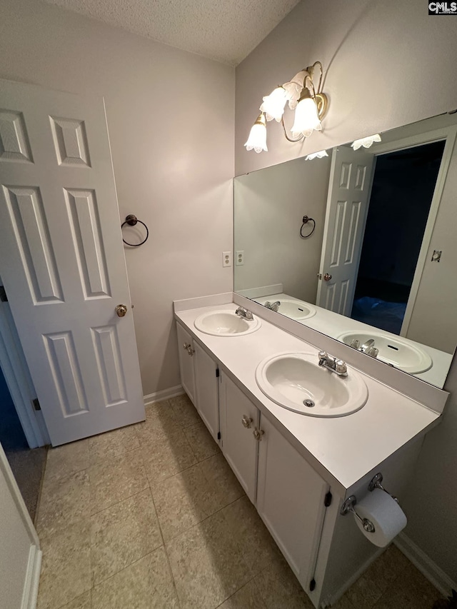 bathroom with double vanity, a textured ceiling, and a sink