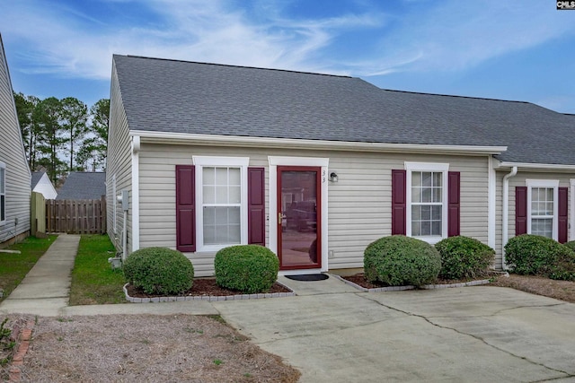 view of front of home with roof with shingles, a patio area, and fence