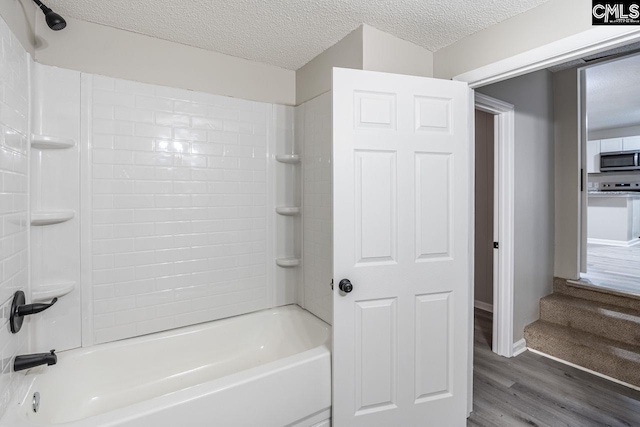 full bathroom featuring a textured ceiling, wood finished floors, and shower / tub combination