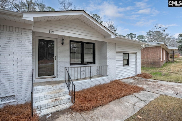 view of exterior entry featuring a porch, crawl space, and brick siding