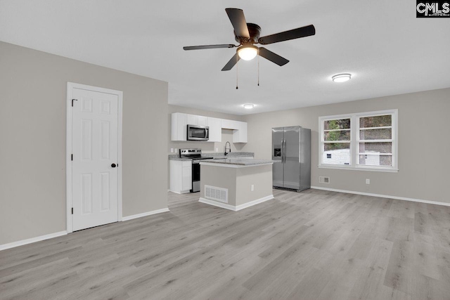 kitchen with visible vents, open floor plan, a kitchen island with sink, stainless steel appliances, and light countertops