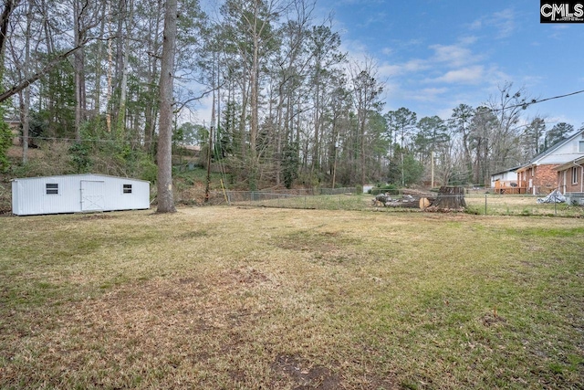 view of yard with a shed, fence, and an outbuilding