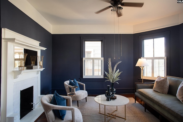 living area with ceiling fan, a fireplace, plenty of natural light, and wood finished floors