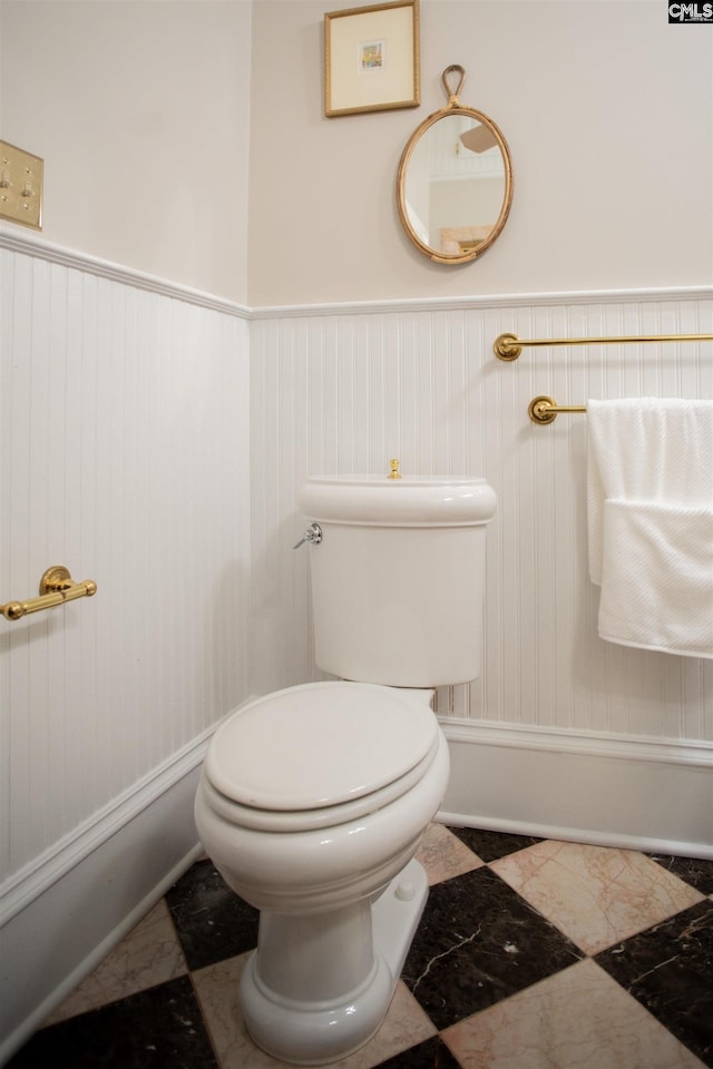 half bath featuring toilet and a wainscoted wall