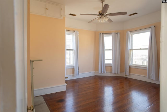 unfurnished room featuring dark wood-type flooring, visible vents, and plenty of natural light