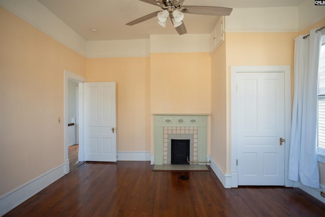 unfurnished living room with baseboards, dark wood finished floors, and a tiled fireplace