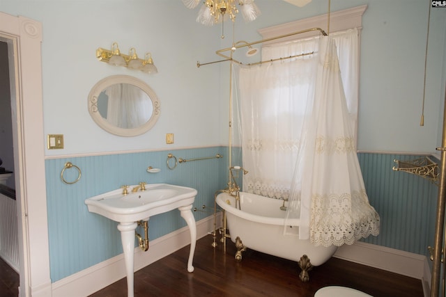 full bathroom with a freestanding tub, wainscoting, and wood finished floors