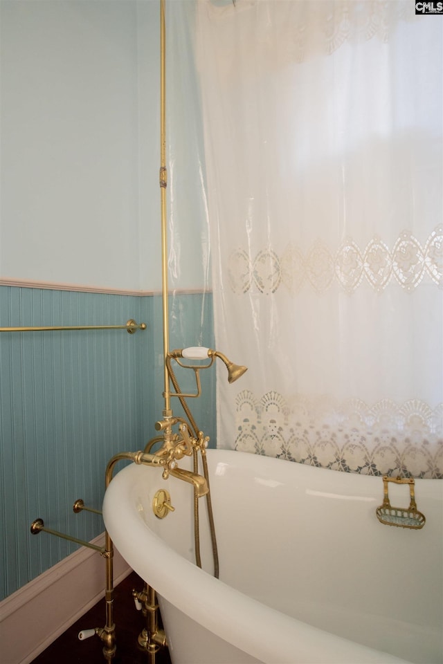 bathroom with a soaking tub and wainscoting