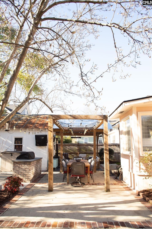 exterior space with exterior kitchen, outdoor dining area, and fence