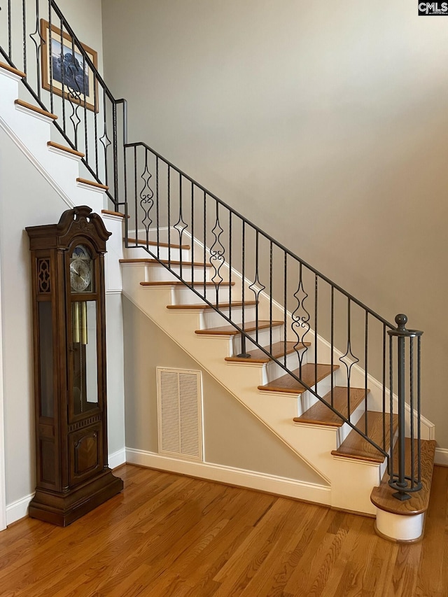 stairs with wood finished floors, visible vents, and baseboards