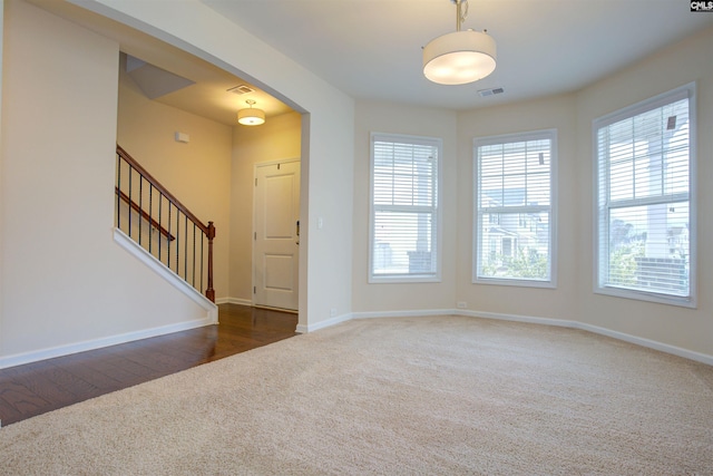 foyer entrance featuring stairs, dark colored carpet, visible vents, and baseboards